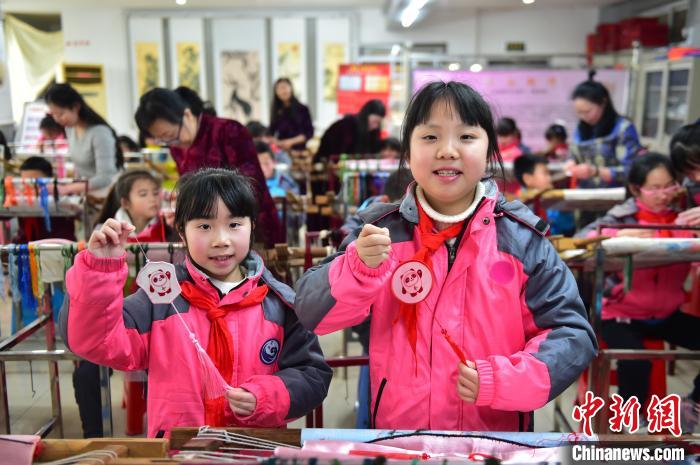 圖為小學生展示繡制好的2022年北京冬奧會吉祥物“冰墩墩”形象?！∮髟屏?攝