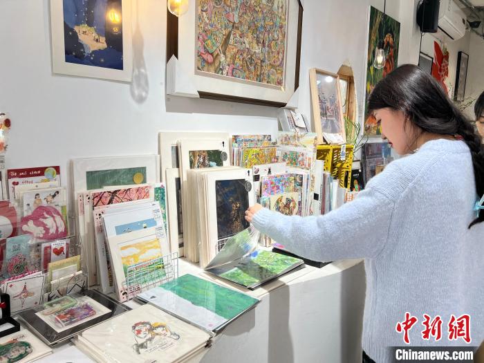 圖為藝術(shù)品商店內(nèi)，顧客挑選插畫作品。　鐘旖 攝