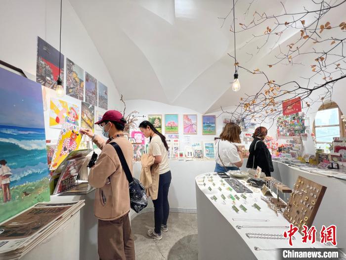 圖為藝術(shù)品商店內(nèi)，顧客挑選插畫作品?！＄婌?攝