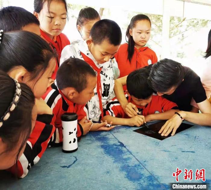 圖為朱增平(右一)教學(xué)生創(chuàng)作鍥金畫。(資料圖) 受訪者供圖