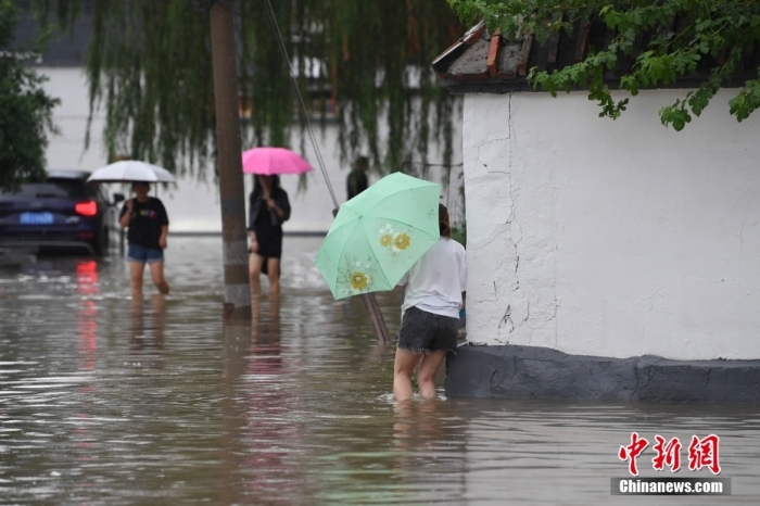 7月31日，市民行走在雨中的北京房山區(qū)瓦窯頭村。北京市氣象臺(tái)當(dāng)日10時(shí)發(fā)布分區(qū)域暴雨紅色預(yù)警信號(hào)。北京市水文總站發(fā)布洪水紅色預(yù)警，預(yù)計(jì)當(dāng)日12時(shí)至14時(shí)，房山區(qū)大石河流域?qū)⒊霈F(xiàn)紅色預(yù)警標(biāo)準(zhǔn)洪水。<a target='_blank' href='/'><p  align=