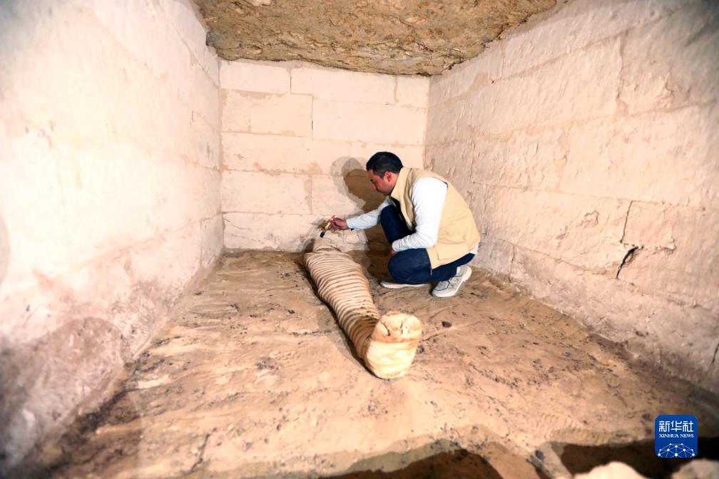 10月15日，在埃及明亞省考古現(xiàn)場，考古人員清理一座石鑿墓中的木乃伊。新華社發(fā)（艾哈邁德·戈馬攝）