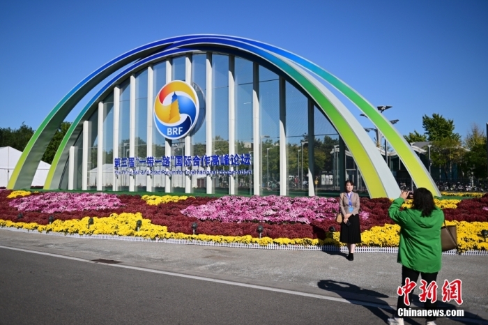 10月15日，北京，工作人員在國家會議中心外的第三屆“一帶一路”國際合作高峰論壇景觀布置前拍照留念。當(dāng)日，位于國家會議中心的第三屆“一帶一路”國際合作高峰論壇新聞中心啟動(dòng)試運(yùn)行。據(jù)悉，第三屆“一帶一路”國際合作高峰論壇將于10月17日至18日在北京舉行。<a target='_blank' href='/'><p  align=