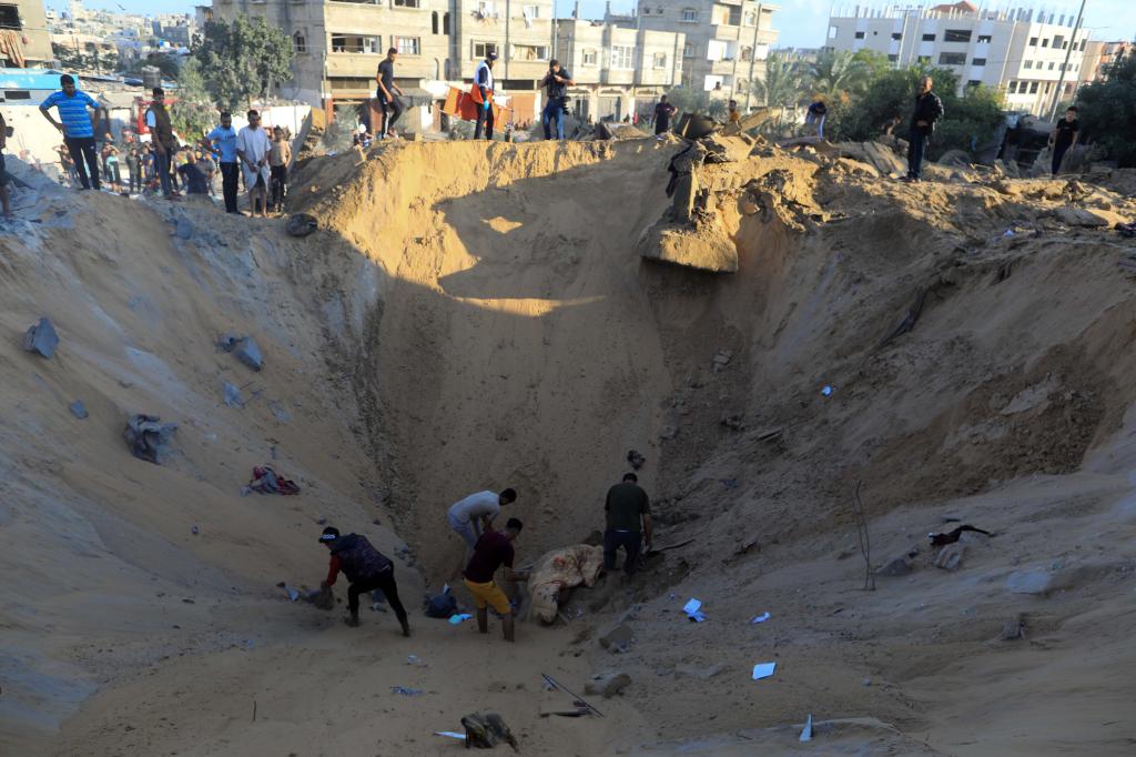 10月16日，在加沙地帶南部城市汗尤尼斯，人們在遭以色列襲擊后的建筑廢墟中救援傷者。 新華社發(fā)（亞西爾·庫迪 攝）
