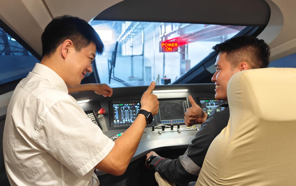 8月25日，在印度尼西亞萬隆的雅萬高鐵德卡魯爾動(dòng)車所內(nèi)，中國(guó)師傅穆振（左）在向印尼火車司機(jī)塞蒂亞萬講解動(dòng)車組出庫(kù)前的上電作業(yè)。