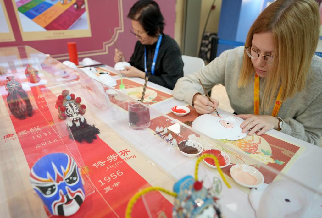 10月16日，在第三屆“一帶一路”國(guó)際合作高峰論壇新聞中心，來(lái)自比利時(shí)的記者（右）體驗(yàn)畫京劇臉譜。新華社記者 王毓國(guó) 攝