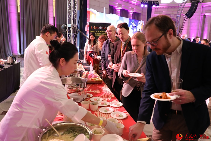 當(dāng)?shù)貢r(shí)間3月7日晚，華盛頓聯(lián)合車站廣場(chǎng)舉行駐美使團(tuán)“使館主廚挑戰(zhàn)賽”。圖為當(dāng)?shù)孛癖娫谥袊?guó)展臺(tái)前體驗(yàn)中國(guó)美食。人民網(wǎng)記者 李志偉攝