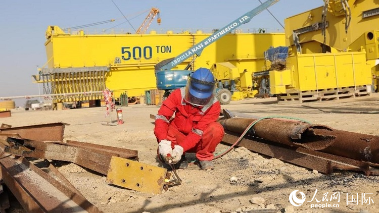 工人正在龍門吊吊裝現(xiàn)場切割金屬件。人民網記者管克江攝