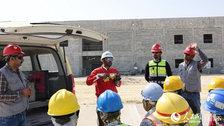 穆薩瓦爾(圖中紅衣人）現(xiàn)場演示工具操作規(guī)范。人民網記者 管克江攝