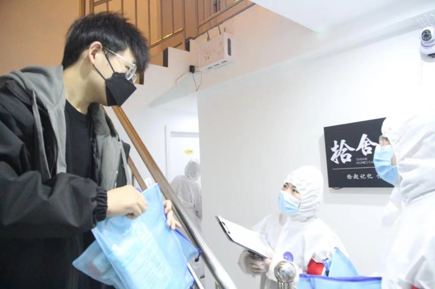 社區(qū)工作人員和志愿者身穿防護服上門送馬應(yīng)龍大健康防疫包。徐帥攝
