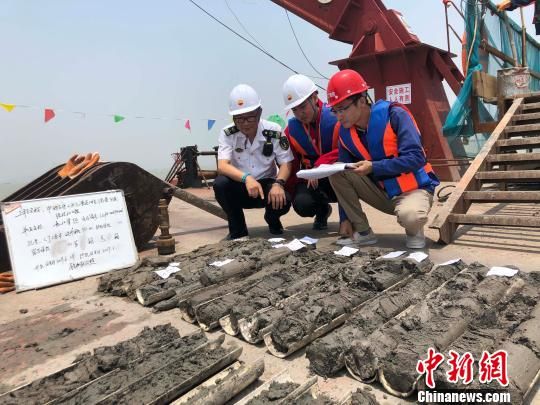圖為勘察設(shè)計人員與海事局工作人員查看巖芯情況?！∥赫?攝