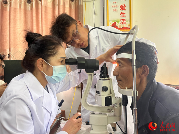 王紅英（左）和團(tuán)隊(duì)成員為達(dá)熱村村民檢查眼睛。人民網(wǎng)記者 杜燕飛攝