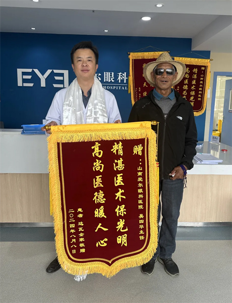 達(dá)瓦老人向吳四華（左）贈送錦旗。受訪者供圖