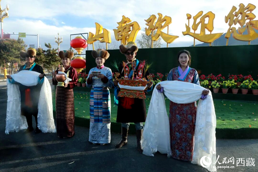 扎西曲登社區(qū)的居民在“山南歡迎您”標(biāo)志前，手持潔白哈達(dá)和切瑪，列隊迎接來自區(qū)內(nèi)外的游客，用最隆重的禮儀開啟一場沉浸式藏歷新年民俗體驗之旅。人民網(wǎng)記者 吳雨仁攝