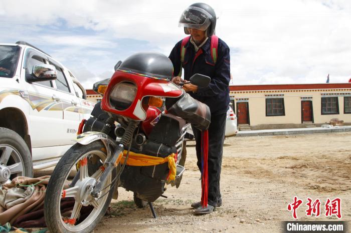 圖為白瑪準(zhǔn)備騎摩托車巡湖?！≮w朗 攝