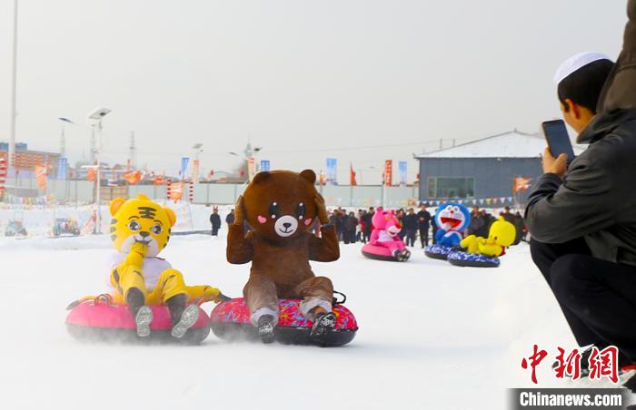 圖為臨夏市南龍鎮(zhèn)馬家莊村舉辦的鄉(xiāng)村文化旅游節(jié)上，游客穿著卡通服裝在體驗(yàn)雪上飛碟項(xiàng)目。近年來(lái)，臨夏州形成了“春賞花、夏避暑、秋摘果、冬玩雪”的全季節(jié)旅游產(chǎn)品體系。(資料圖) 高展 攝