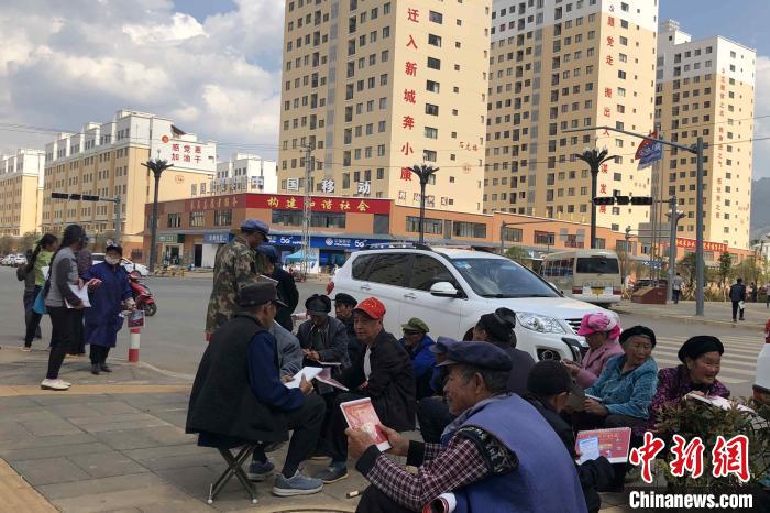 圖為會澤縣城易地扶貧搬遷安置點(diǎn)內(nèi)，老人們聚在廣場上聊天，身后是他們的新家。　繆超 攝