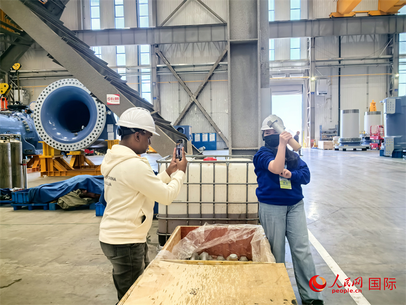 外媒記者掂量廠房內(nèi)的巨型螺栓。人民網(wǎng) 楊春燕攝