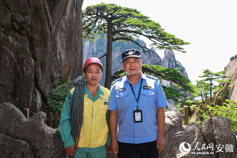 全國道德模范李培生（左）和胡曉春在迎客松前合影。人民網(wǎng)記者 張俊攝