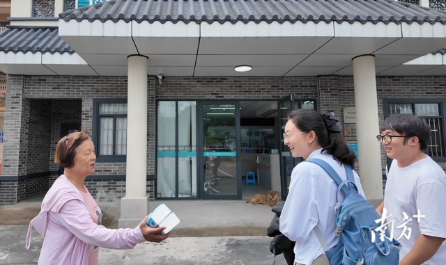 公共服務(wù)組成員王櫻潔（中）和張龍（右）在崖口村衛(wèi)生室前跟村民打招呼。