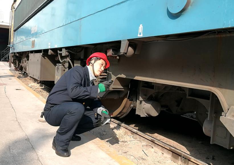 韓文盛全神貫注檢查機(jī)車走行部。