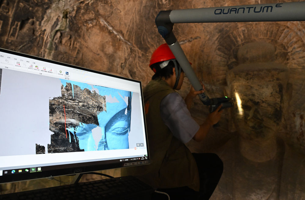 2025年4月9日，武漢大學(xué)文化遺產(chǎn)智能計算實驗室團(tuán)隊成員在魏字洞使用關(guān)節(jié)臂掃描儀對佛像進(jìn)行數(shù)字化掃描。圖片來源新華社