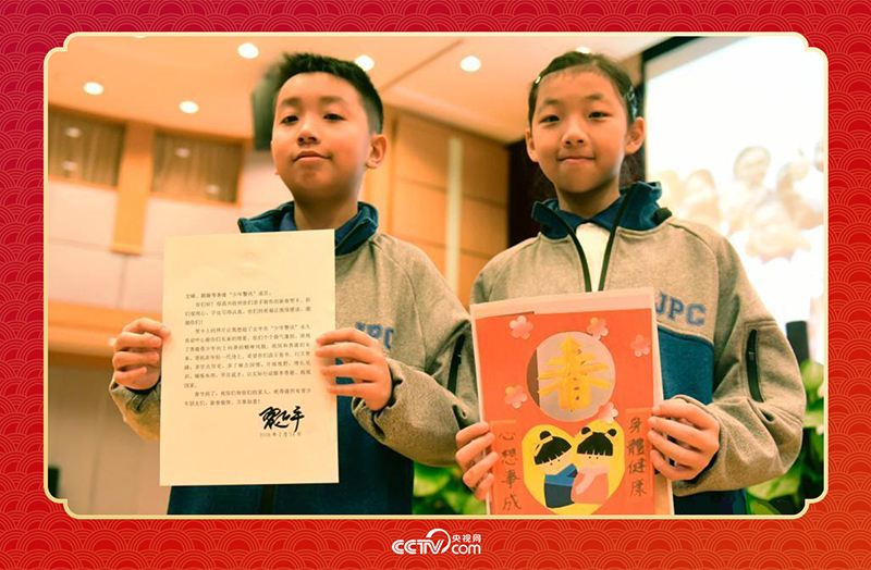 圖為香港“少年警訊”成員郭宏晞（左）展示習主席回信、羅顥凝（右）展示送給習主席的賀卡并合影。