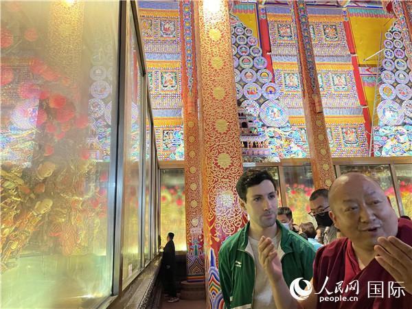 7月25日，省級非物質(zhì)文化遺產(chǎn)項目塔爾寺酥油花的代表性傳承人朋措堅參（右）在塔爾寺酥油花館講解酥油花的制作過程。人民網(wǎng) 謝瑩攝