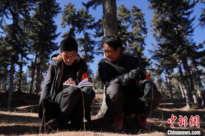 圖為桑杰加(左)和同事記錄巡查結(jié)果。　馬銘言 攝