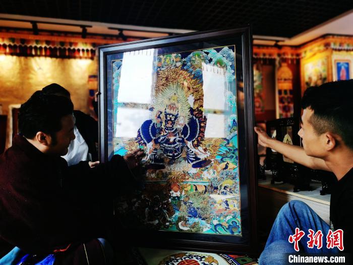 圖為久美尖措(左)與徒弟們展示唐卡作品。　張?zhí)砀?攝