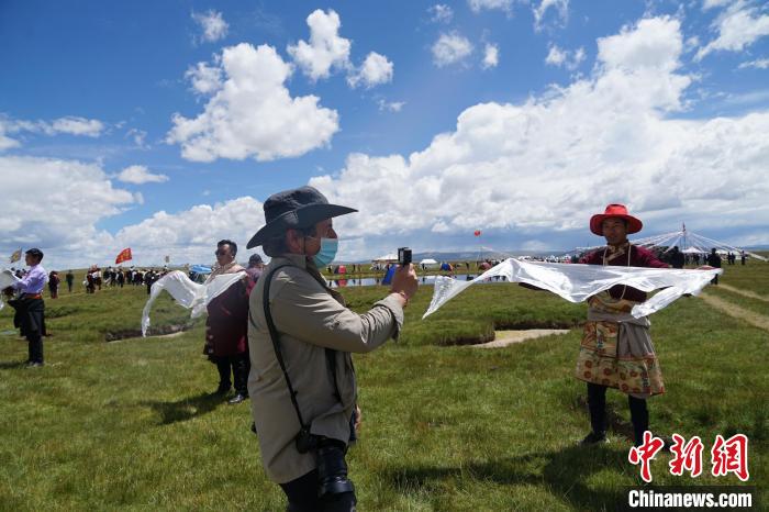 圖為一名外籍?dāng)z影師記錄當(dāng)?shù)夭刈鍤g迎儀式?！●R銘言 攝