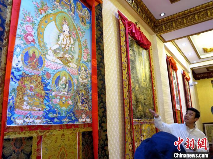 圖為完德尖措展示熱貢龍樹畫苑內(nèi)的唐卡?！?zhí)砀?攝
