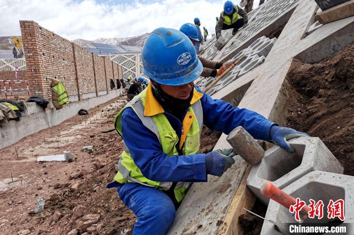圖為光伏發(fā)電項目施工區(qū)工人在護坡鋪設空心磚。　李雋 攝