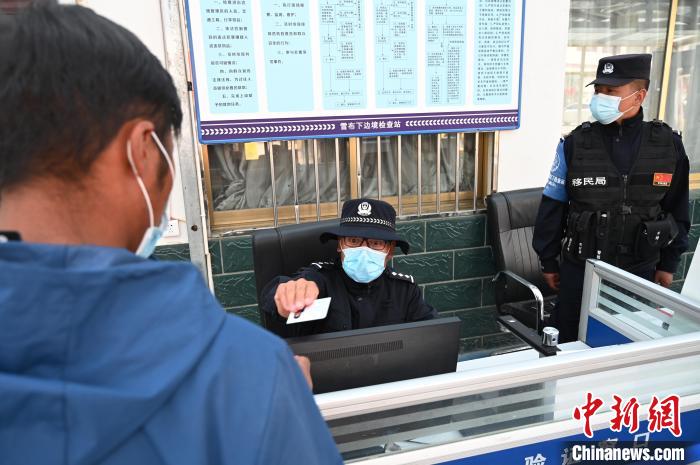 圖為移民管理警察登記完身份信息后將證件歸還給行人?！≮w朗 攝