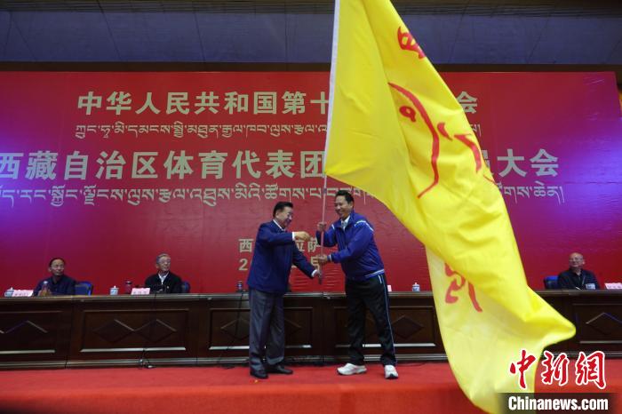 西藏自治區(qū)副主席甲熱·洛桑丹增授代表團(tuán)團(tuán)旗，西藏自治區(qū)體育局局長(zhǎng)尼瑪次仁接旗?！∪轿木?攝