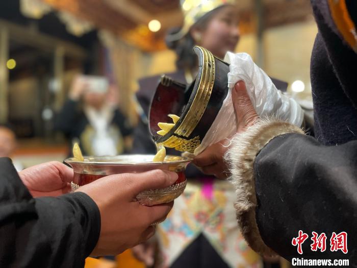 圖為主人在碗中斟滿青稞酒?！∪轿木?攝