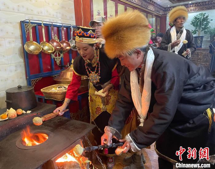 圖為人們在火上烤節(jié)日美食“結(jié)達”?！∪轿木?攝