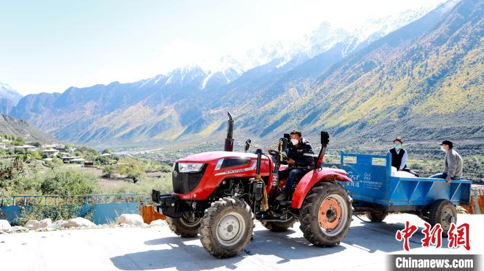 圖為工作人員將把加工完成的糌粑運(yùn)送至村民手中?！〖卫杩h融媒體中心供圖