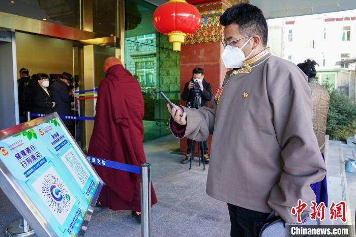 圖為政協(xié)委員掃場所碼進(jìn)入會場?！〗w波 攝