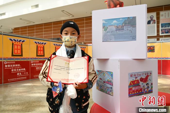 圖為一名獲獎學(xué)生與自己的繪畫作品合影?！≮w朗 攝