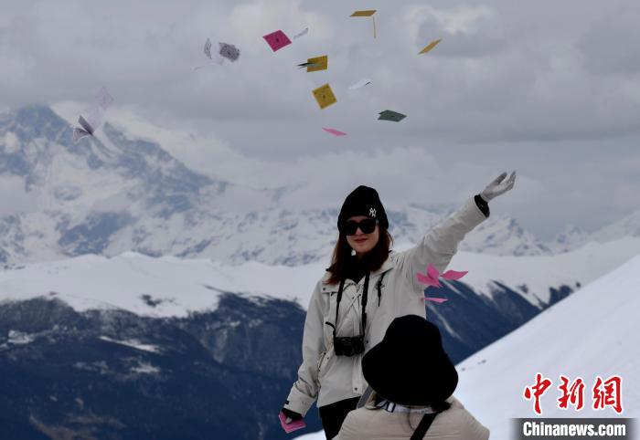 圖為5月14日，游客在西藏林芝色季拉山觀景臺(tái)拋灑“隆達(dá)”(風(fēng)馬旗，藏族民眾的一種祈福方式)?！±盍?攝