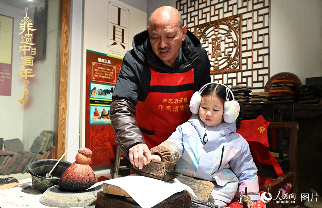 2025年1月27日，河南開封朱仙鎮(zhèn)木版年畫藝人尹國法指導小朋友研習年畫印制技藝。朱仙鎮(zhèn)木版年畫源自漢唐壁畫藝術，是中國木版年畫的鼻祖。2006年5月20日，朱仙鎮(zhèn)木版年畫經(jīng)國務院批準列入第一批國家級非物質文化遺產(chǎn)名錄。人民網(wǎng)記者 王玉興攝
