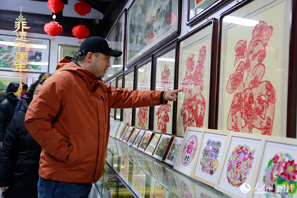 2025年1月23日，游客在天津楊柳青古鎮(zhèn)欣賞傳統(tǒng)剪紙作品，感受指尖上的古老藝術。人民網(wǎng)記者 崔新耀攝