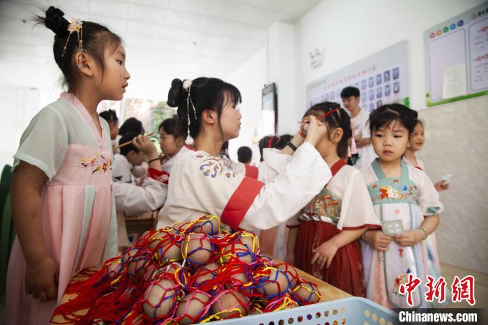 圖為幼兒園的老師們穿上漢服為小朋友們戴上彩蛋，寓意著幸福安康。　董觀生 攝